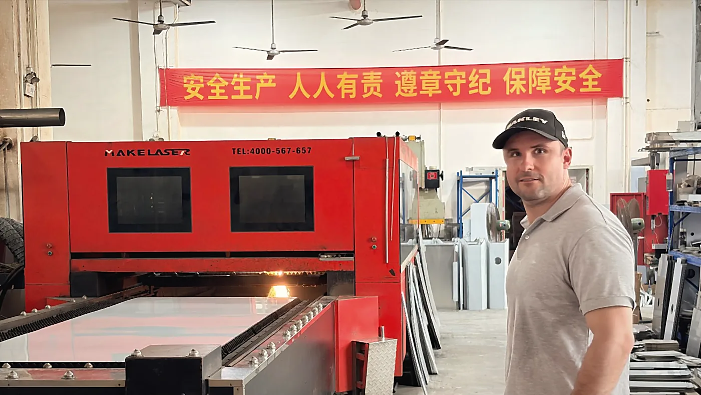 Sebastian Kirsch in a production hall in front of a laser cutting machine