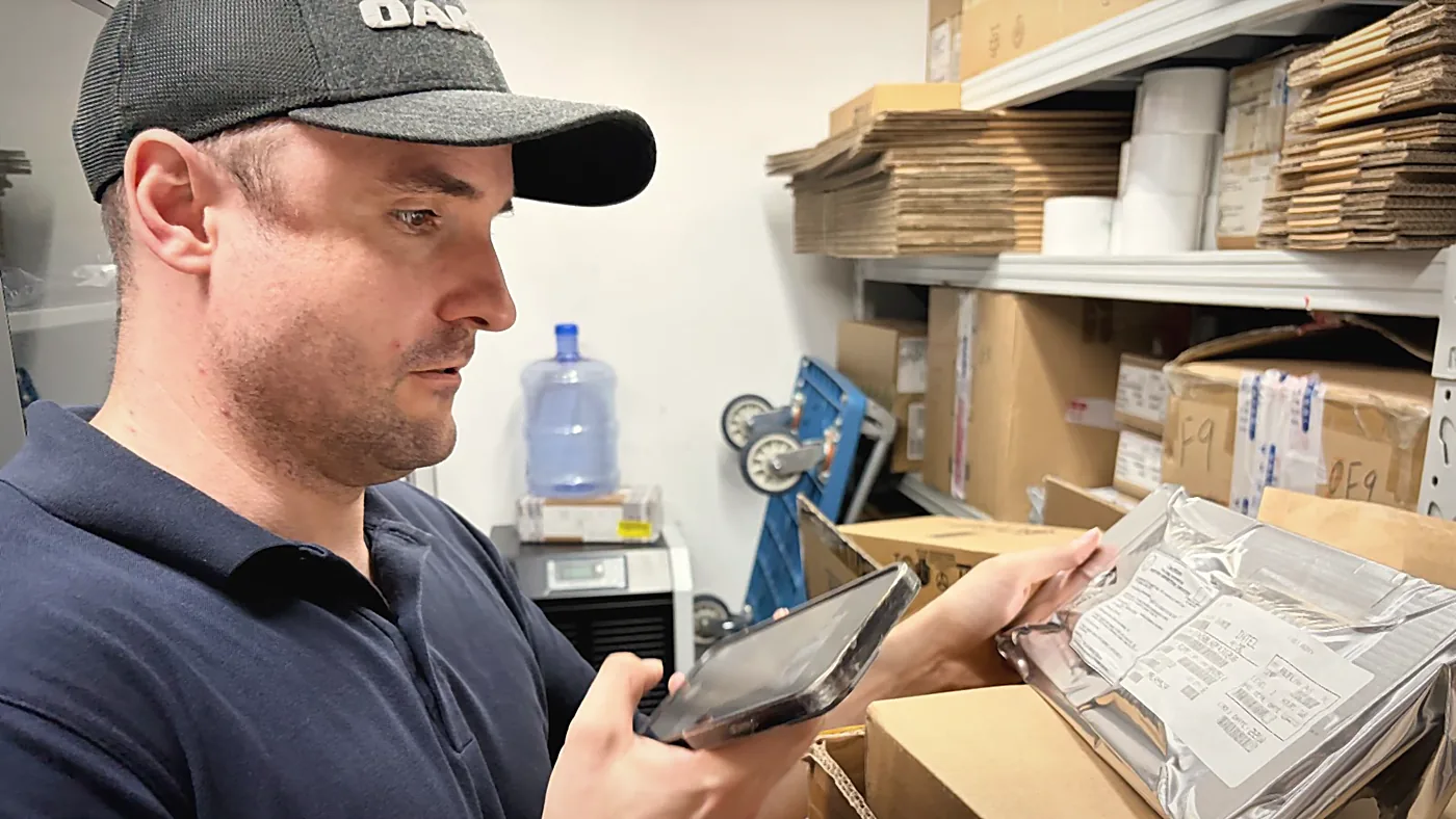 Sebastian Kirsch checking a packaged circuit board against the data on his tablet in a supplier warehouse