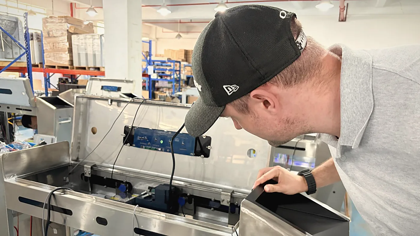 Sebastian Kirsch checking the wiring inside a stainless steel unit in a workshop